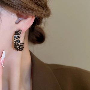 Close-up of leopard print C-shape earrings made from polished acetate on a model
