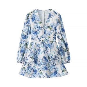 Detail view of the floral print pattern and ruffled hem on blue V-neck dress