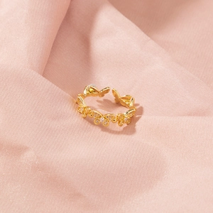 Macro shot of a gold-plated butterfly ring with sparkling cubic zirconia on peach fabric