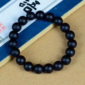 Vue détaillée d'un bracelet de perles en bois de santal noir mat sur fond culturel