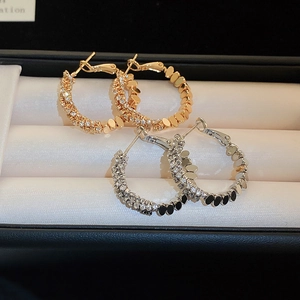 Close-up of gold and silver hoop earrings with pavé zircons in a jewelry gift box