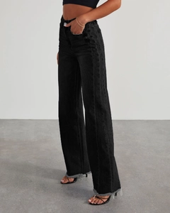 Vue latérale du jean noir à taille haute et jambe large avec ourlet brut effiloché