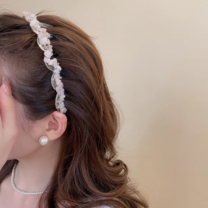 Close-up of a wavy acrylic hairband with pink irregular stones on brown wavy hair
