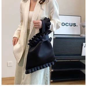 Detail of elegant black pleated handbag with ruffle trim and soft satin texture finish