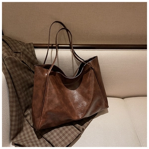 Detail of dark caramel faux leather tote bag with vintage texture and long shoulder strap