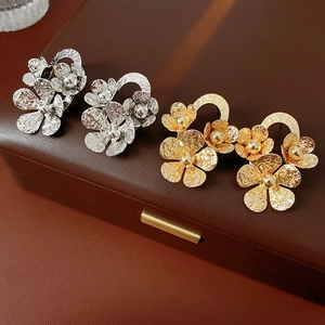 Detail view of gold and silver floral earrings with hammered texture on leather
