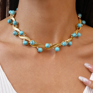 Detail of a vintage gold wavy necklace with turquoise beads and rhinestones on a neck