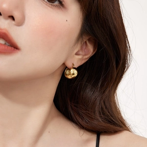 Close-up of minimalist 18K gold-plated spherical hoop earring on model's ear
