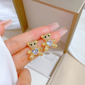 Macro detail of bear earring with gold base, white zircon pave and purple heart stone
