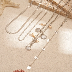 Detail von silbernen Schichtketten mit Schnecken, Muschel-Anhängern und Pailletten
