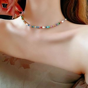 Detail of 18K gold plated necklace with colorful beads and baroque pearls on model