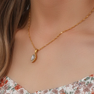 Close-up of golden leaf eye pendant with marquise zircon on a twisted necklace
