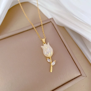 Macro view of gold tulip pendant with iridescent petals and crystals in a jewelry box