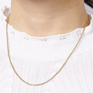 Detail shot of a delicate gold stainless steel pearl chain necklace on a model's neck