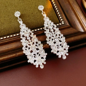 Detalle de pendientes de borla plateados con diamantes de imitación en un marco vintage