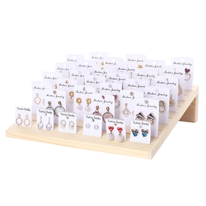 Tiered solid wood earring display stand holding a large assortment of fashion jewelry pieces