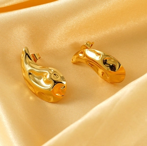Macro shot of gold-plated drop earrings with irregular molten metal lava texture