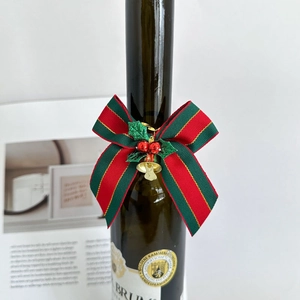 Christmas striped ribbon bow with holly berries and gold bell on a gift bottle