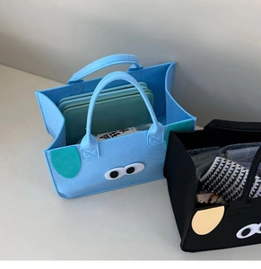 Detailed view of two cute cartoon felt storage bags in light blue and black with animal ears