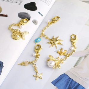Gold plated sun and bee bag charms with pearls and sea themed lobster clasp