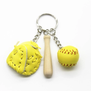 Detailed view of yellow leather glove, wooden bat, and baseball keychain set on white back