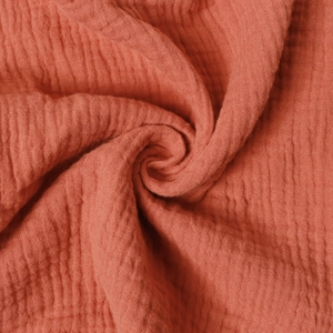 Macro shot of breathable double-layer cotton muslin fabric texture in deep orange
