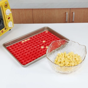 Detail of red heart silicone mold with baked goods on a metal tray in a home kitchen
