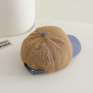 Detail view of the brown plush cap with blue corduroy brim and adjustable metal buckle