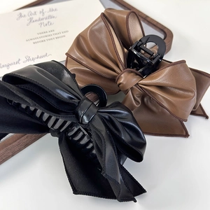 Detail shot of vintage leather bow claw clips in black and brown colors on white background