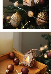 Close-up of glowing wooden house ornaments and glass acorns on a festive Christmas tree