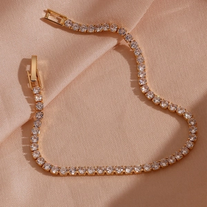 Classic 14K gold plated tennis bracelet with zircon stones on pink silk background