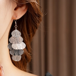 Close-up of silver layered leaf tassel earrings worn by a model with a hook design
