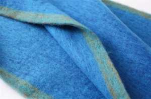 Detailed close-up of blue cashmere-like fabric with brown edge and fuzzy wool texture