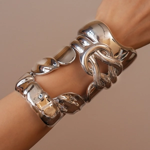 Polished silver metal bracelets with twisted geometric design worn on a model's wrist