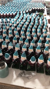 Mass-produced garden gnome figurines with blue hats and rifles in a production setting