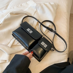 Detail of black glossy leather baguette bag with silver twist lock and small pouch