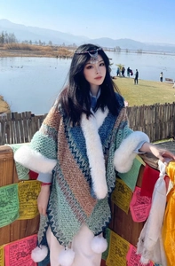 Detail of ethnic geometric pattern cape with white faux fur trim and tassels