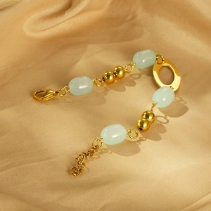 Detail of beaded bracelet featuring green resin beads and gold hollow lip metal charms