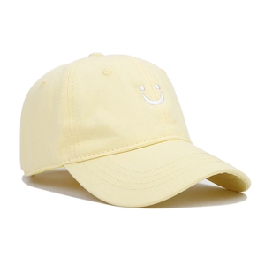 Close-up of yellow cotton baseball cap with white smiley face embroidery and twill texture