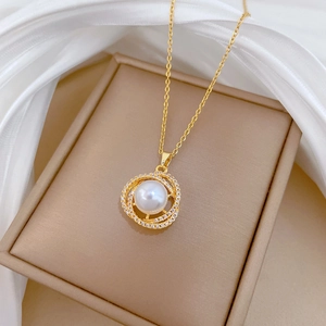 Detailed close-up of a bird's nest pearl necklace with pavé zircons on a jewelry box