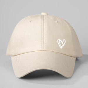 Close-up of beige cotton baseball cap featuring a minimal white heart print on side