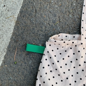 Detail der gepunkteten Tragetasche mit grünem Seitenband auf dem Asphalt-Hintergrund