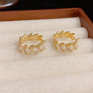 Eleganti orecchini a spiga dorati con zirconi e perle bianche in una scatola di legno