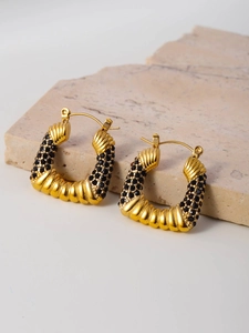 Detailed macro shot of vintage gold C-shaped earrings with black pave-set crystals