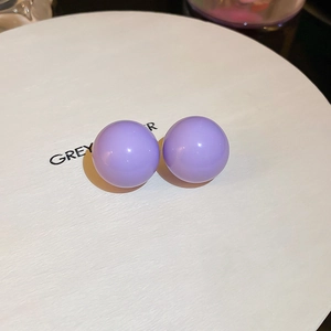 Close-up of lavender purple ball stud earrings with smooth polished finish on white box