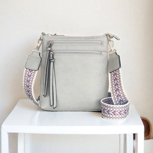 Dettaglio della borsa a tracolla grigia con zip a frange e tracolla jacquard colorata