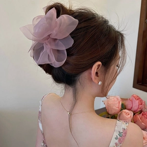 Detailed view of a soft pink mesh flower hair claw clip worn on a bun hairstyle