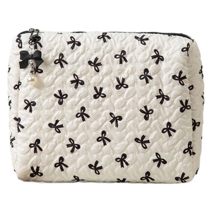 Quilted white cosmetic bag with black bow patterns and elegant pearl zipper pendant