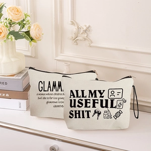 Off-white canvas makeup bags with fun slogans and black zippers in home setting