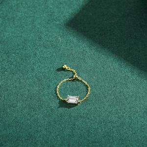 Adjustable S925 silver gold chain ring with emerald-cut zircon on green background
